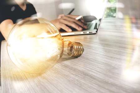 light bulb with designer hand working with laptop computer and creative business strategy as concept