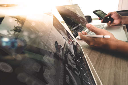 designer hand working with digital tablet and laptop computer and book stack and eye glass on wooden desk as conceptの写真素材