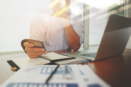 business documents on office table with smart phone and laptop computer and graph business diagram...
