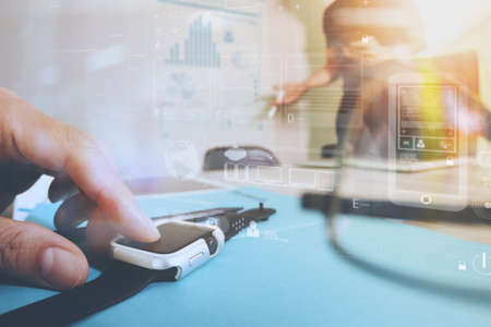 business presentation meeting on office table with smart watch and laptop computer and graph business diagram and three colleagues discussing data in the backgroundの写真素材