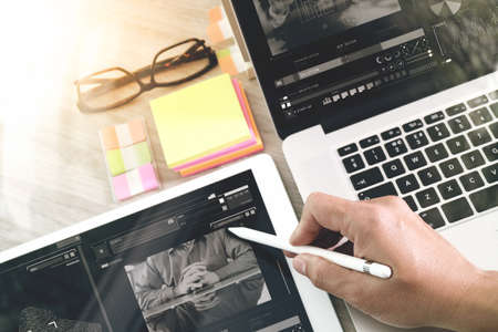 businessman hand working with digital tablet computer and memo note and laptop computer with digital business strategy layer effect on wooden desk as conceptの写真素材