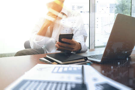 business documents on office table with smart phone and digital laptop computer and graph business diagram and man working in the backgroundの写真素材