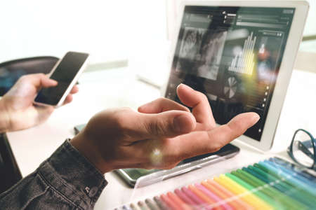 Website designer working digital tablet and computer laptop  with smart phone and graphics design diagram on marble desk as conceptの写真素材