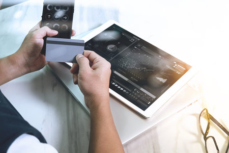 Businessman hands holding plastic credit card and using digital tablet and laptop computer with...