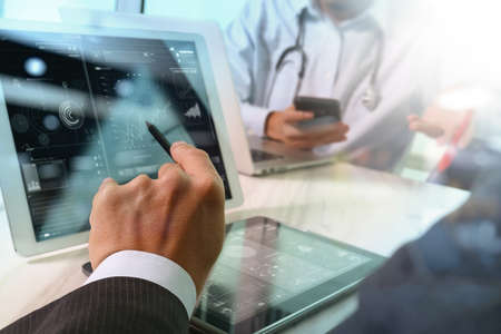 Medical technology network team concept. Doctor hand working with smart phone modern digital tablet and laptop computer with graphics  chart interface, Sun flare effect photoの写真素材