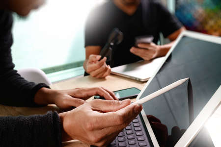 two colleague web designer discussing data and digital tablet docking keyboard and computer laptop with smart phone and design diagram on marble desk,sun light effectの写真素材