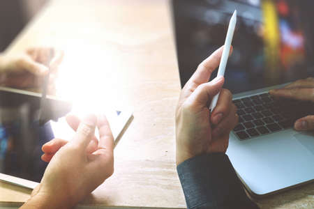 Businessman hand making presentation with his colleagues and business tablet digital computer at the office as concept, sun flare effectの写真素材