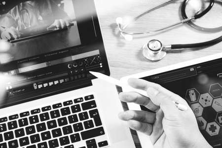 Medical network technology concept. Doctor hand working with stethoscope and laptop computer digital tablet with medical chart interface. View from top and close up photo. Double exposure effects, black whiteの写真素材