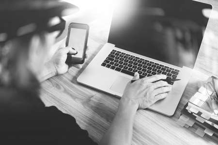 designer hand attending video conference with laptop computer and smart phone at desk in office, black whiteの写真素材