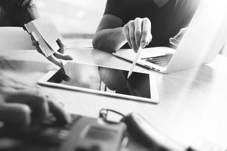 two colleague web designer discussing data and digital tablet and computer laptop with smart phone and design diagram on marble desk,telephone foreground, black and whiteの写真素材