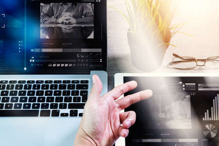 businessman hand working with digital tablet computer and memo note and laptop computer with digital business strategy layer effect on wooden desk as conceptの写真素材
