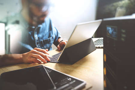 Co working process, entrepreneur team working in creative office space. using digital tablet docking keyboard and laptop with smart phone on marble desk,light beam effectの写真素材