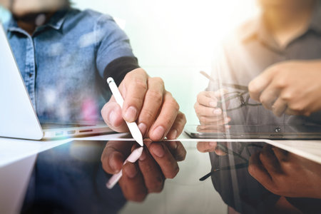 Team work concept,businessman hand attending video conference in modern office.Digital tablet laptop computer design smart phone using. Sun effects, Blurred backgroundの写真素材