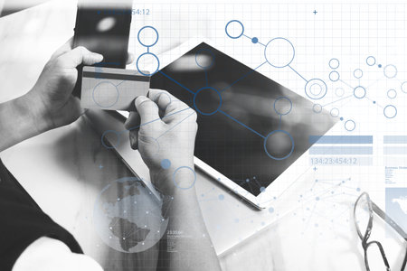 Businessman hands holding plastic credit card and using digital tablet and laptop computer with...