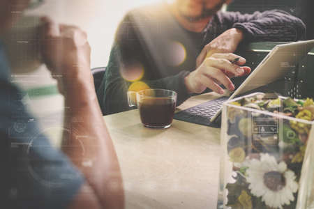 Office coffee break with two designer colleagues sitting chatting over cups of coffee,flower vase,digital tablet docking smart keyboard on marble desk,filters effect filmの写真素材