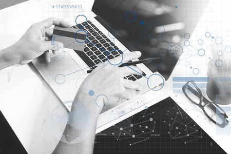 Businessman hands holding plastic credit card and using digital tablet and laptop computer with...