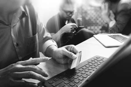 Coworking process, entrepreneur team working in creative office space. using digital tablet docking keybord and laptop with smartphone on marble desk,light beam effectの写真素材
