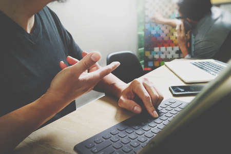 Coworking process, entrepreneur team working in creative office space. using digital tablet docking keybord and laptop with smartphone on marble desk,light beam effectの写真素材