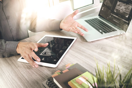 Businessman hand attending video conference with laptop computer and tablet computer at desk in...