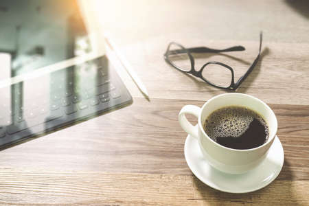 Coffee cup and Digital table dock smart keyboard,eyeglasses,stylus pen on wooden table,filter effectの写真素材