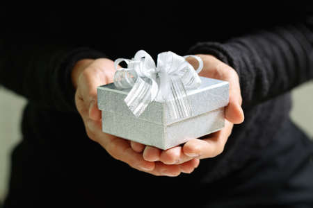 gift giving,man hand holding a gift box in a gesture of giving.blurred background,bokeh effectの写真素材