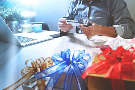 Gift giving,medical doctor Hand with credit card and hand with gift. Gift delivery, surprise,laptop computer and smart phone on mable desk,filter film effectの写真素材