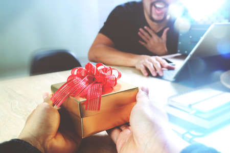 Gift Giving.business creative designer hand giving his colleague Christmas present in office,filter film effect