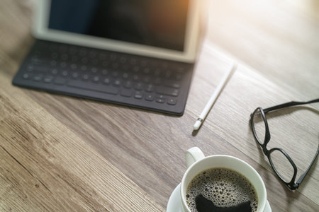 Coffee cup and Digital table dock smart keyboard,eyeglasses,stylus pen on wooden table,filter effect