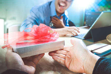 Gift Giving.Patient hand or Team giving a gift to a surprised Medical Doctor in hospital office,filter film effectの写真素材