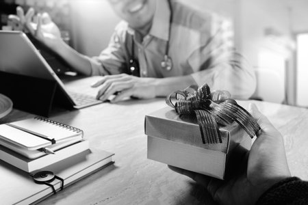 Gift Giving.Patient hand or Team giving a gift to a surprised Medical Doctor in hospital office,black and whiteの写真素材