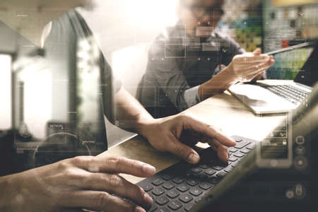 Coworking process, entrepreneur team working in creative office space. using digital tablet docking keybord and laptop with smartphone on marble desk,light beam effectの写真素材