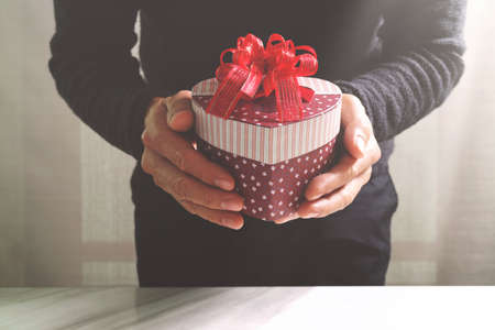 gift giving,man hand holding a gift box in a gesture of giving.blurred background,bokeh effectの写真素材