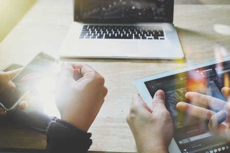 Businessman hand making presentation with his colleagues and business tablet digital computer at the office as concept, sun flare effectの写真素材