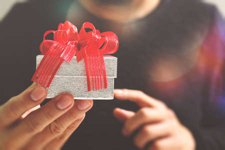 gift giving,man hand holding a gift box in a gesture of giving.blurred background,bokeh effectの写真素材
