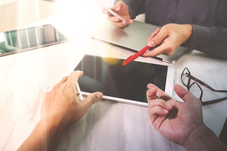 Photo website graphic designer hand working with his team make new project in studio.Modern laptop extend screen digital tablet smart phone on marble table. sun flare effectの写真素材
