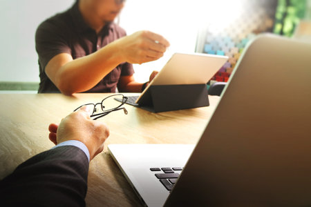 two colleague web designer discussing data and digital tablet docking keyboard and computer laptop with smart phone and design diagram on marble desk,sun light effectの写真素材
