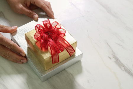 gift giving,man hand holding a gift box in a gesture of giving on white gray marble table background