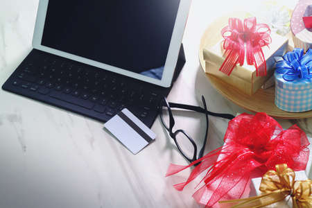 Tablet computer docking smrt keyboard with credit card and eyeglassamong christmas gifts on marble background,filter film effectの写真素材