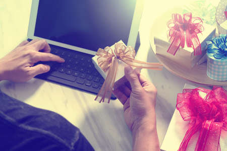 Gift giving Creative Hand typing and hand with gift. Gift delivery, surprise,tablet computer docking smart keyboard smart phone on mable desk,vintage film effectの写真素材