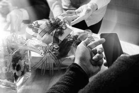Gift giving Creative Hand using smart phone and co worker choosing gift. Gift delivery,office party,on marble meeting table,black whiteの写真素材