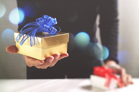 gift giving,man hand holding a gift box in a gesture of giving.blurred background