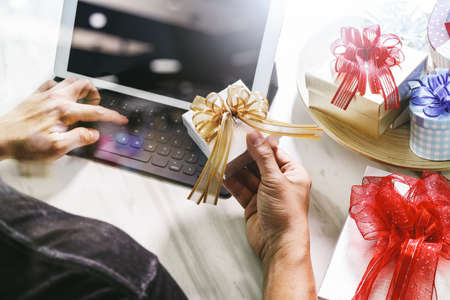 Gift giving Creative Hand typing and hand with gift. Gift delivery, surprise,tablet computer docking smart keyboard smart phone on mable desk,filter film effectの写真素材