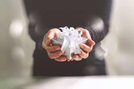 gift giving,man hand holding a gift box in a gesture of giving.blurred background,bokeh effectの写真素材