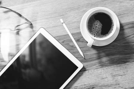 Coffee cup and Digital table dock smart keyboard,eyeglasses,stylus pen on wooden table,filter effect,black whiteの写真素材