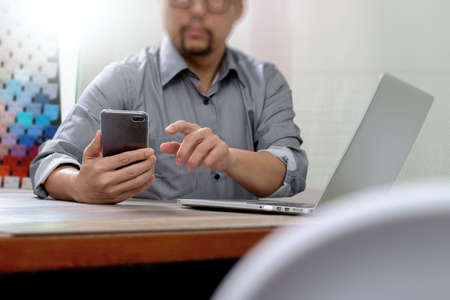 Businessman hand using mobile payments online shopping,pencil,omni channel,laptop computer on wooden desk in modern officeの写真素材