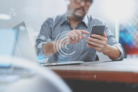 Businessman hand using mobile payments online shopping,omni channel,laptop computer on wooden desk,digital screen graphic virtual icons,graph,diagramの写真素材
