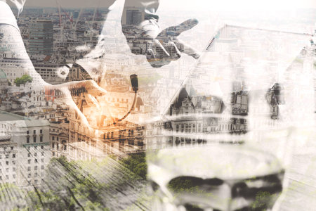 Double exposure of business man using VOIP headset with digital tablet computer docking smart keyboard, concept communication, it support,London city,on wood deskの写真素材
