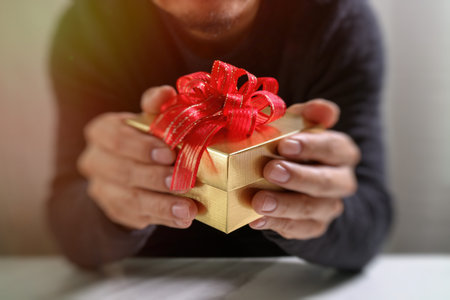 gift giving,man hand holding a gift box in a gesture of giving.blurred background,vintage effectの写真素材
