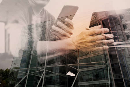 Double exposure of Designer hand using mobile payments online shopping,omni channel,laptop computer on wooden desk,London architecture bulidingsの写真素材