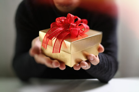gift giving,man hand holding a gift box in a gesture of giving.blurred background,vintage effectの写真素材